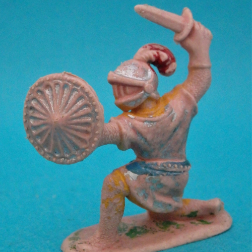 Chevalier à genoux avec épée et bouclier rond.